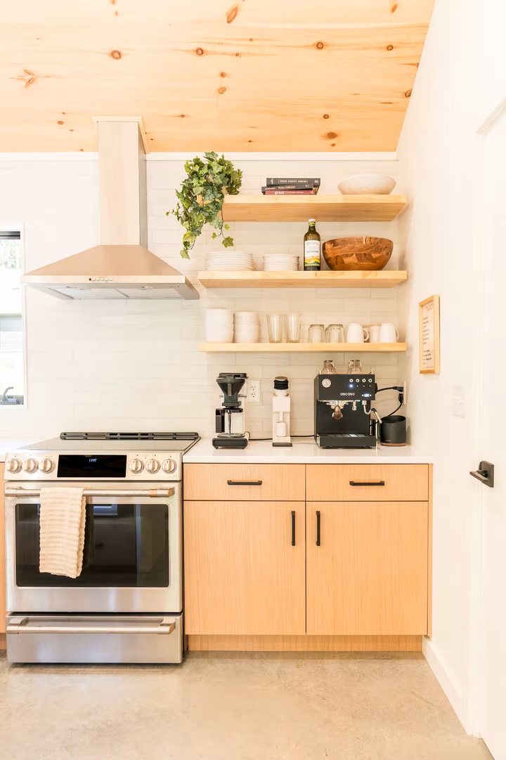 Your kitchen blends warm wood tones with modern appliances and thoughtful details—like an espresso setup ready for your morning ritual and open shelving stocked for easy cooking.
