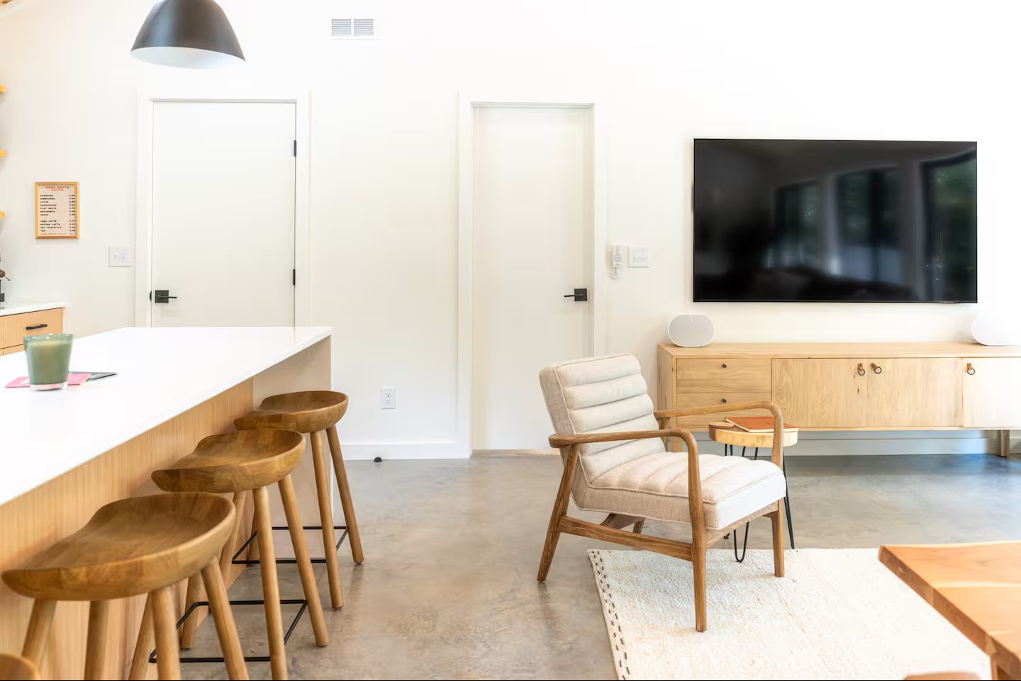 Step into your sleek open-concept space with polished concrete floors and warm wood accents. Enjoy modern comfort with bar seating for casual meals and a cozy lounge chair for relaxing evenings.
