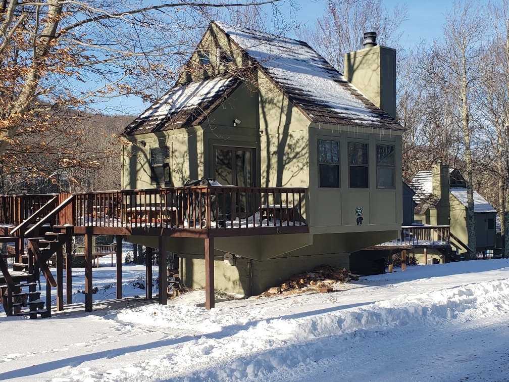 Charming winter retreat nestled in snowy landscape with spacious deck for mountain views.