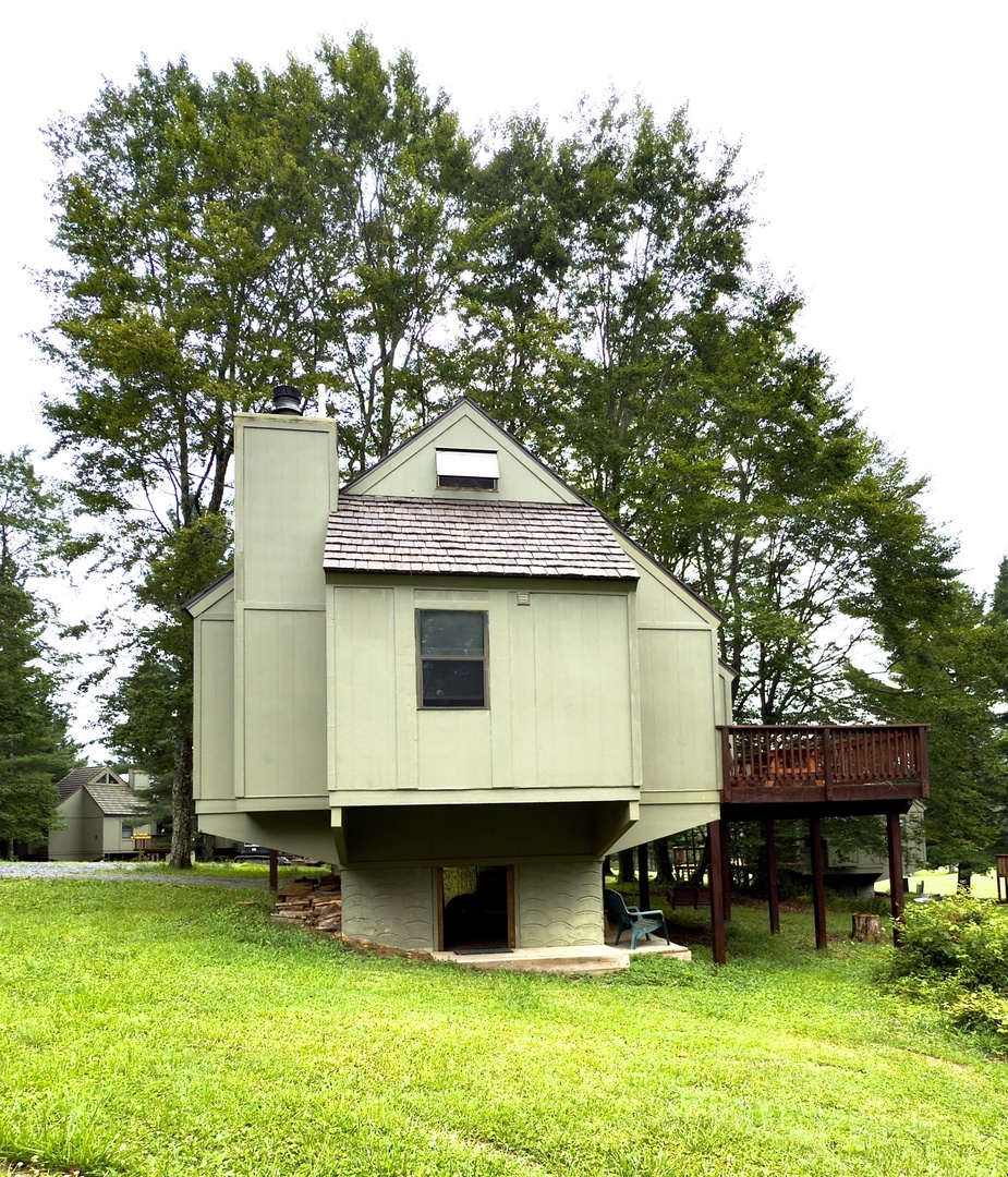 Unique elevated cabin nestled among mature trees in a peaceful residential setting with charming architectural details.