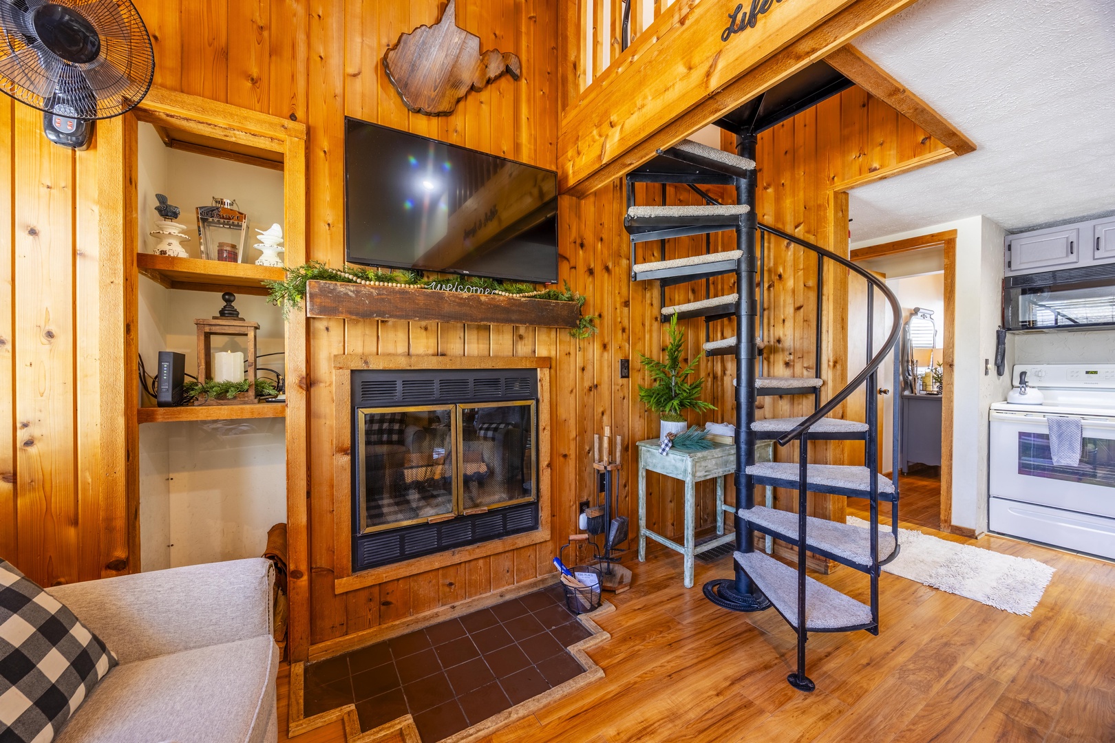 Warm wooden walls and glowing fireplace invite you to relax in this cozy retreat, while a charming spiral staircase leads to your upstairs loft.