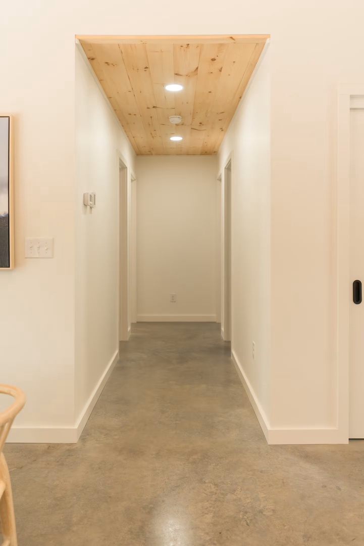 A welcoming hallway leads you through the home, with beautiful natural wood ceiling panels adding warmth overhead. Smooth polished floors stretch ahead, connecting your living spaces effortlessly.