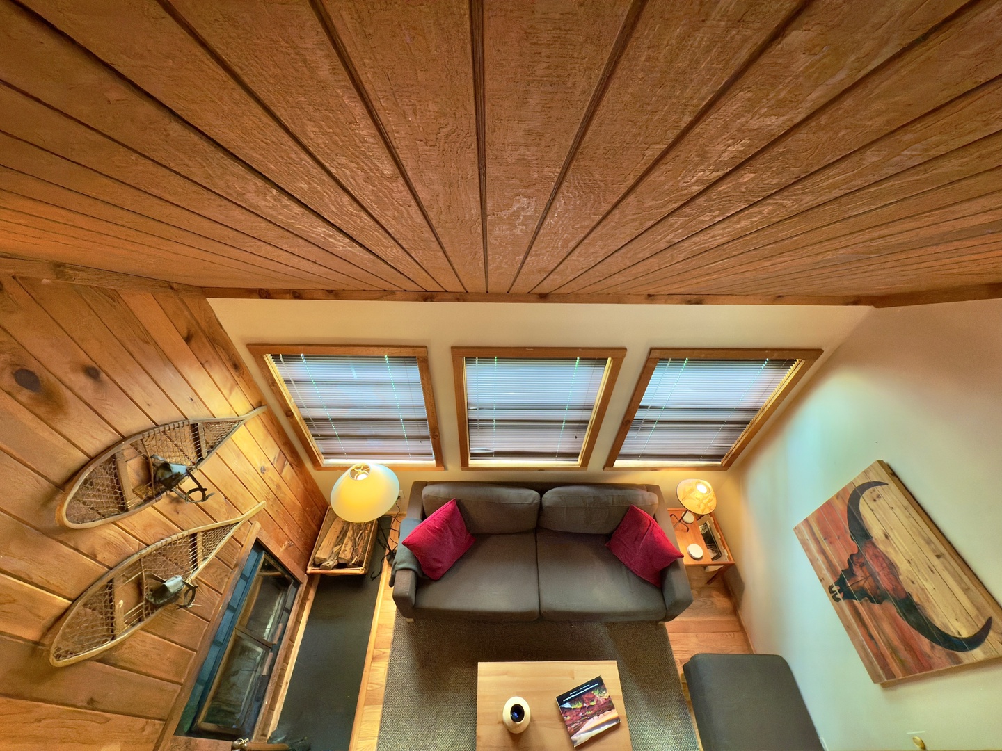 Relax in your cozy attic living room with stunning wood beams overhead, natural skylights, and comfortable seating perfect for unwinding.