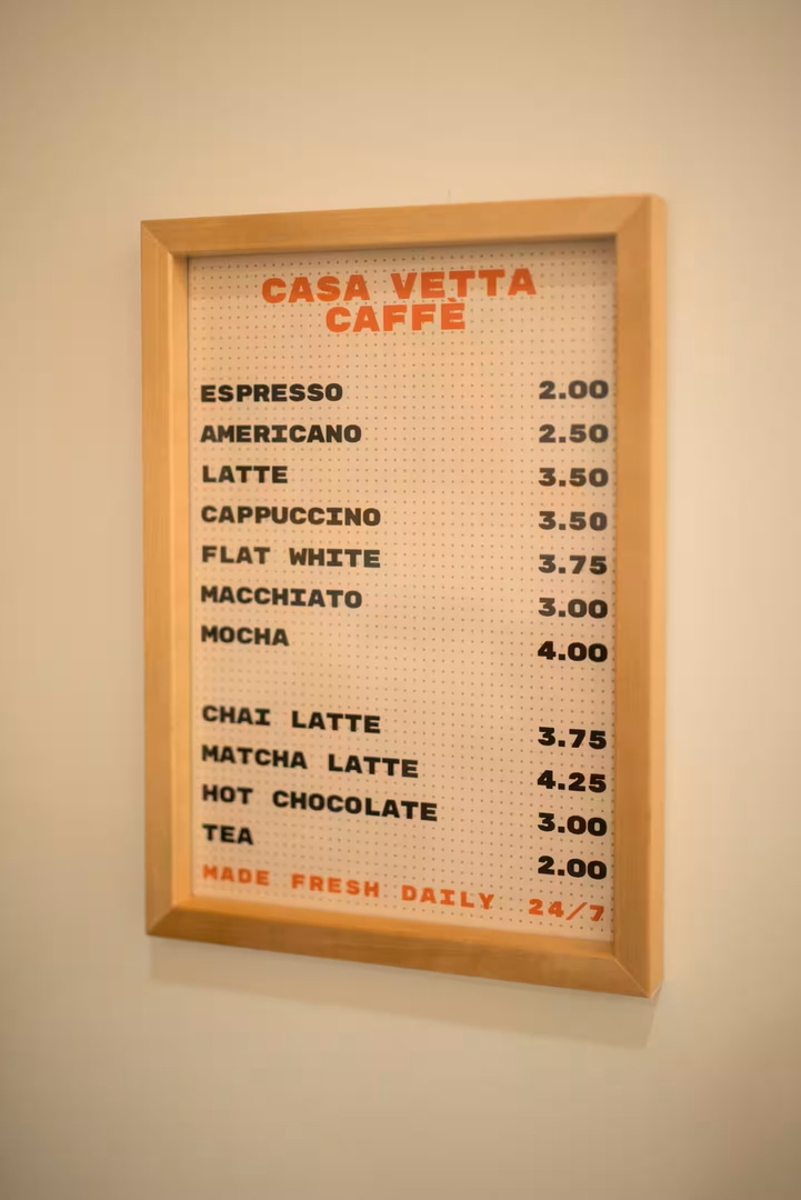 A framed coffee menu hangs on the wall, showcasing artisan beverages available for you to enjoy throughout your stay.