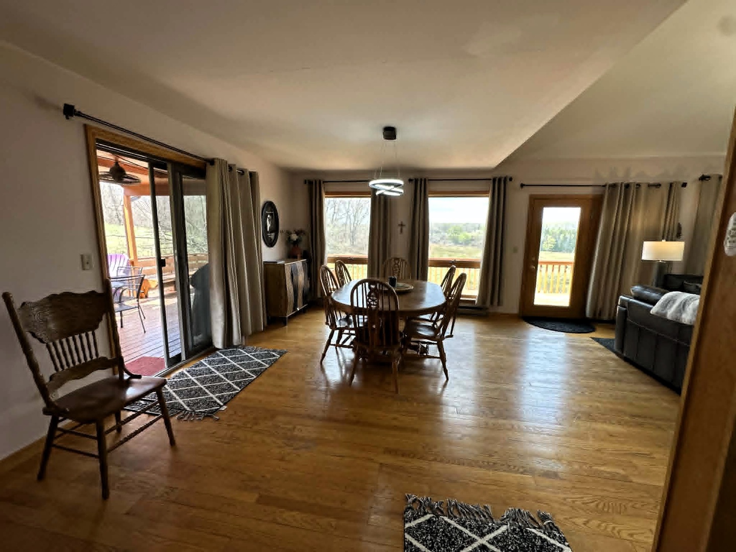 Your spacious open-concept living and dining area features warm hardwood floors and panoramic windows showcasing peaceful countryside views.