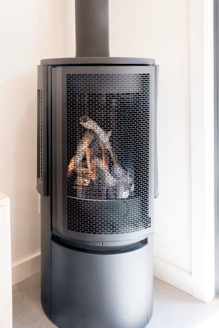 Cozy up beside this sleek freestanding fireplace, where flames flicker behind modern mesh screening, filling your space with inviting warmth and ambiance.