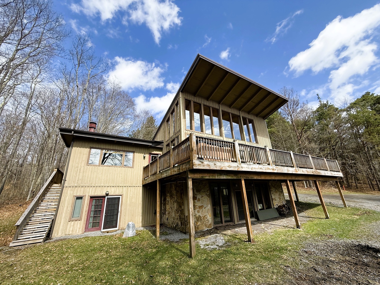 Modern mountain cabin with expansive deck overlooking wooded landscape, featuring contemporary architecture and natural materials.