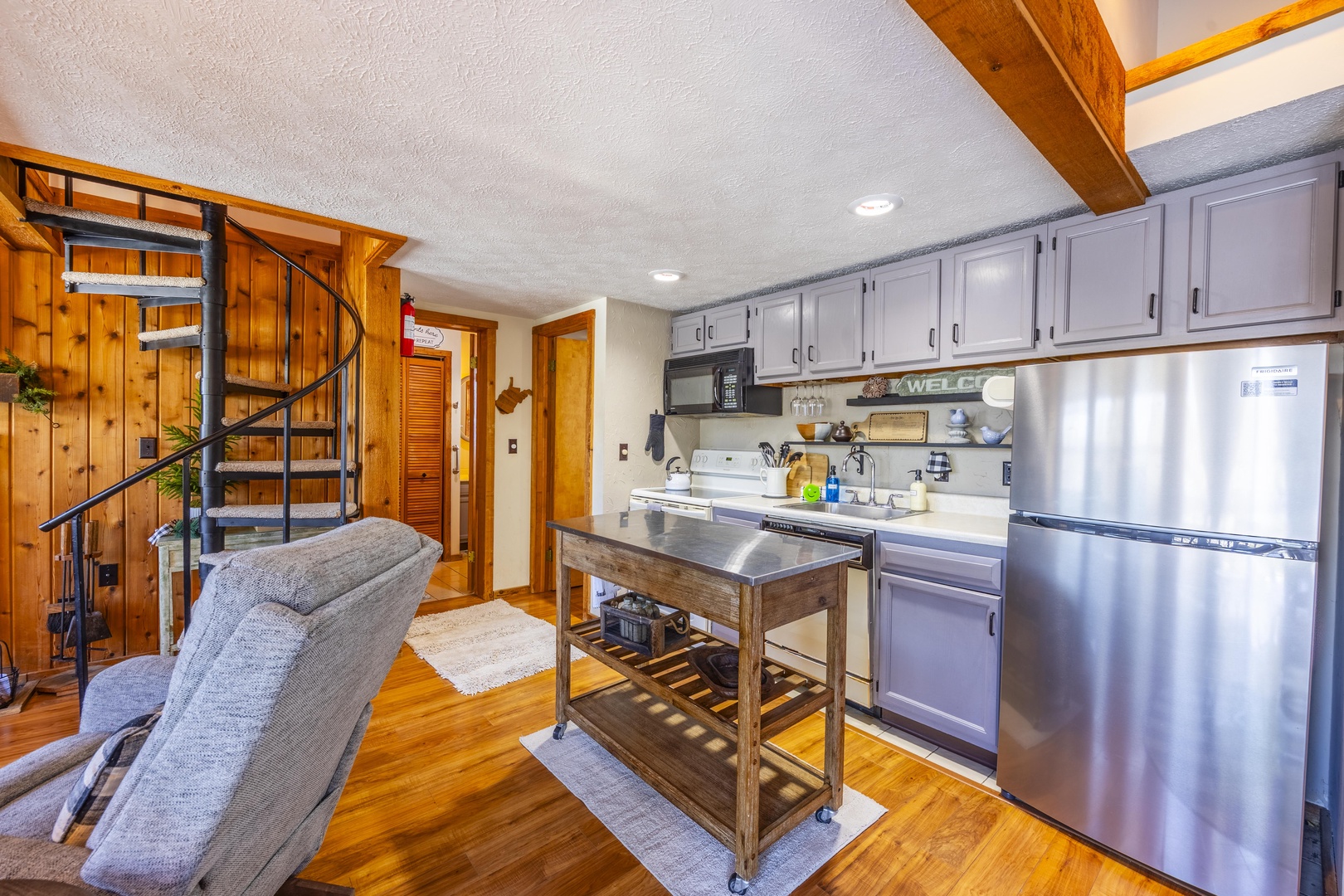 Picture yourself cooking in this charming open kitchen with stainless steel appliances and rustic wood accents. The unique spiral staircase adds character to your cozy mountain retreat.