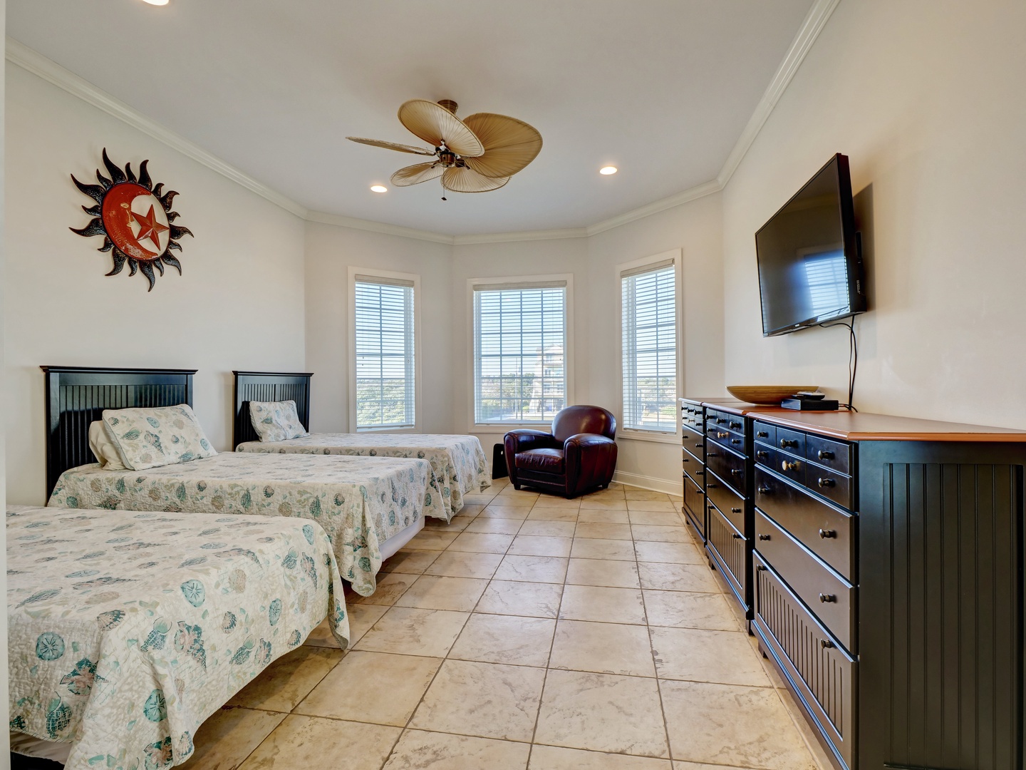 A guest bedroom with three twin-sized beds, a flat-screen TV, and a jack and jill bathroom