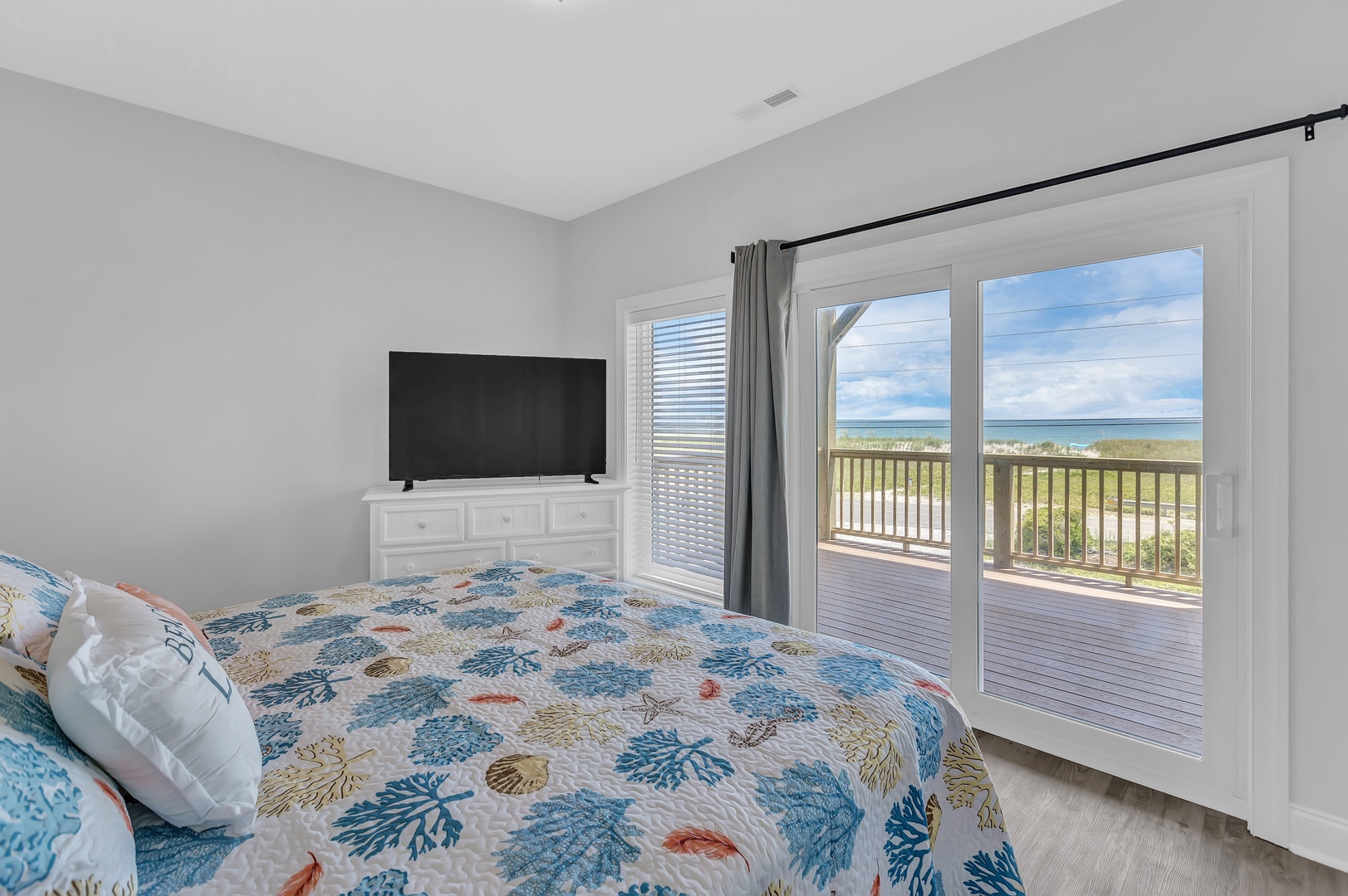 Guest bedroom with king-sized bed, Smart TV, access to a first-floor balcony with ocean views, and an attached bathroom.