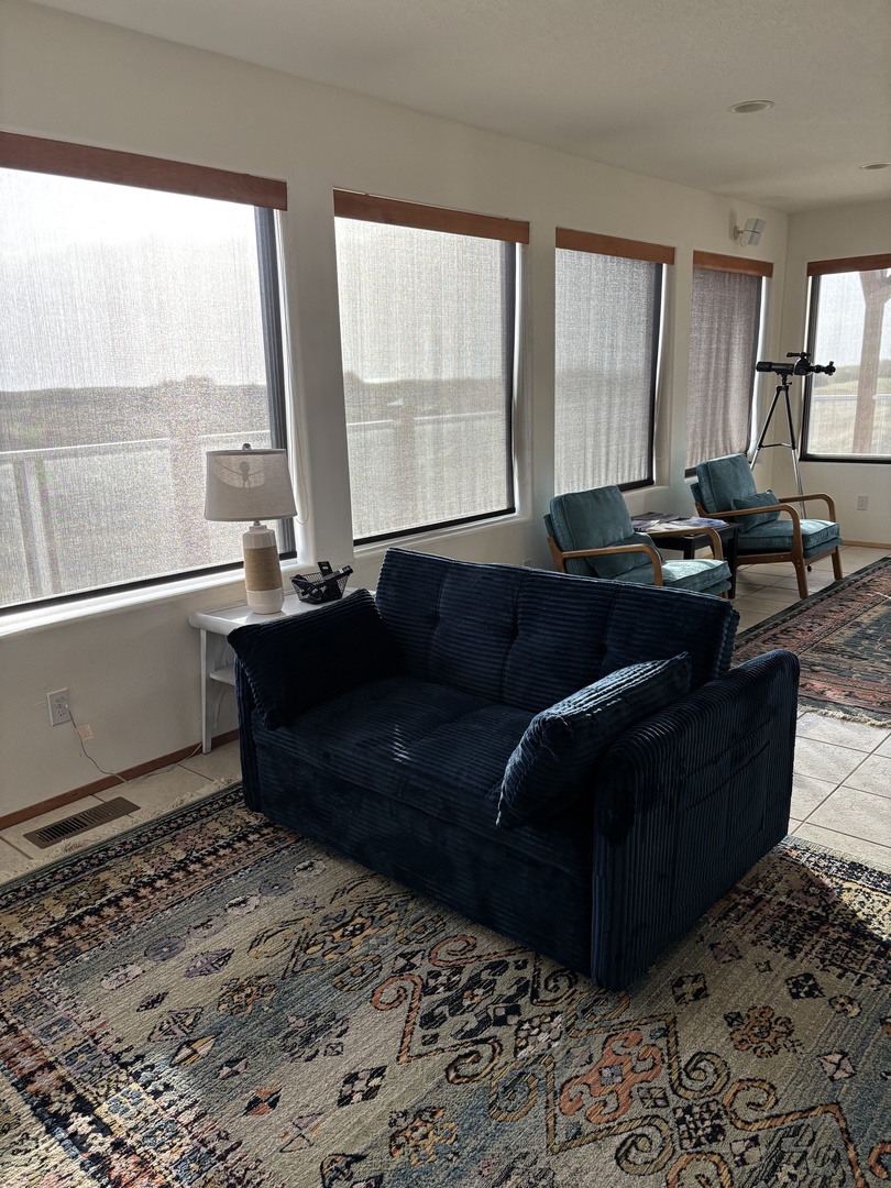 Sink into your plush navy sofa while natural light streams through expansive windows, creating the perfect spot for relaxation.