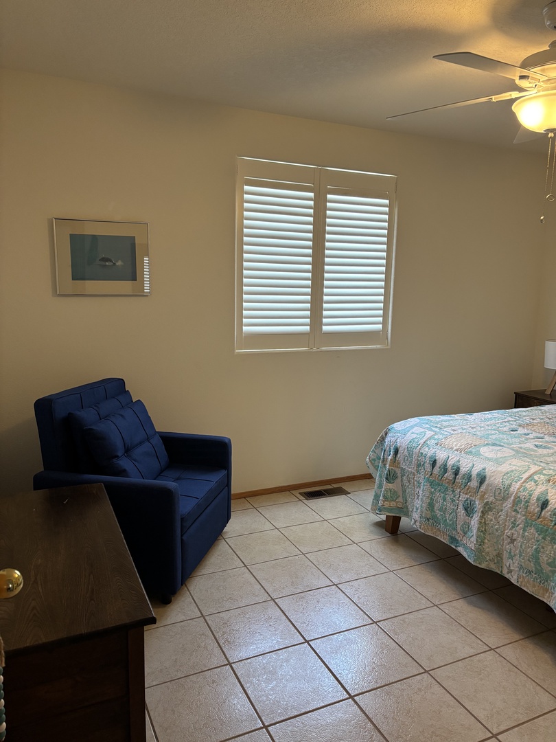 Relax in your comfortable living space with cozy seating and natural light filtering through the window blinds.