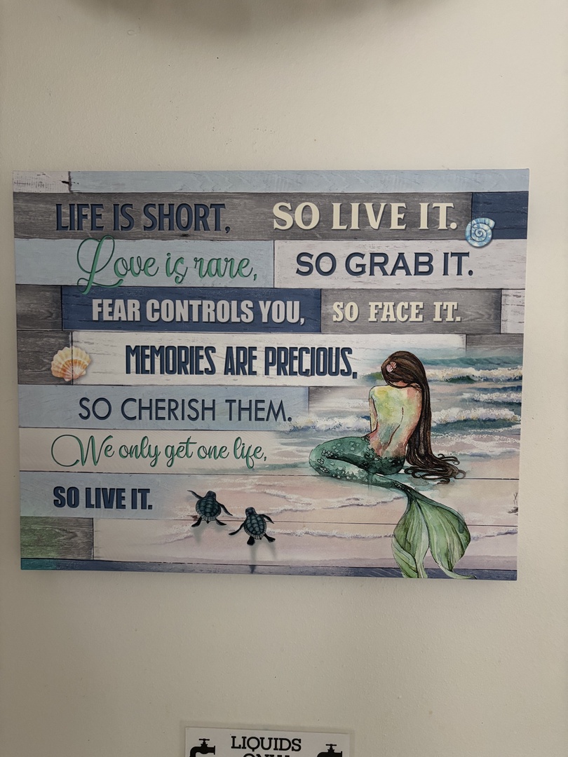 A coastal-inspired sign adorns the wall with a whimsical mermaid and sea turtles, reminding you to embrace each moment and 'so live it' during your beachside escape.