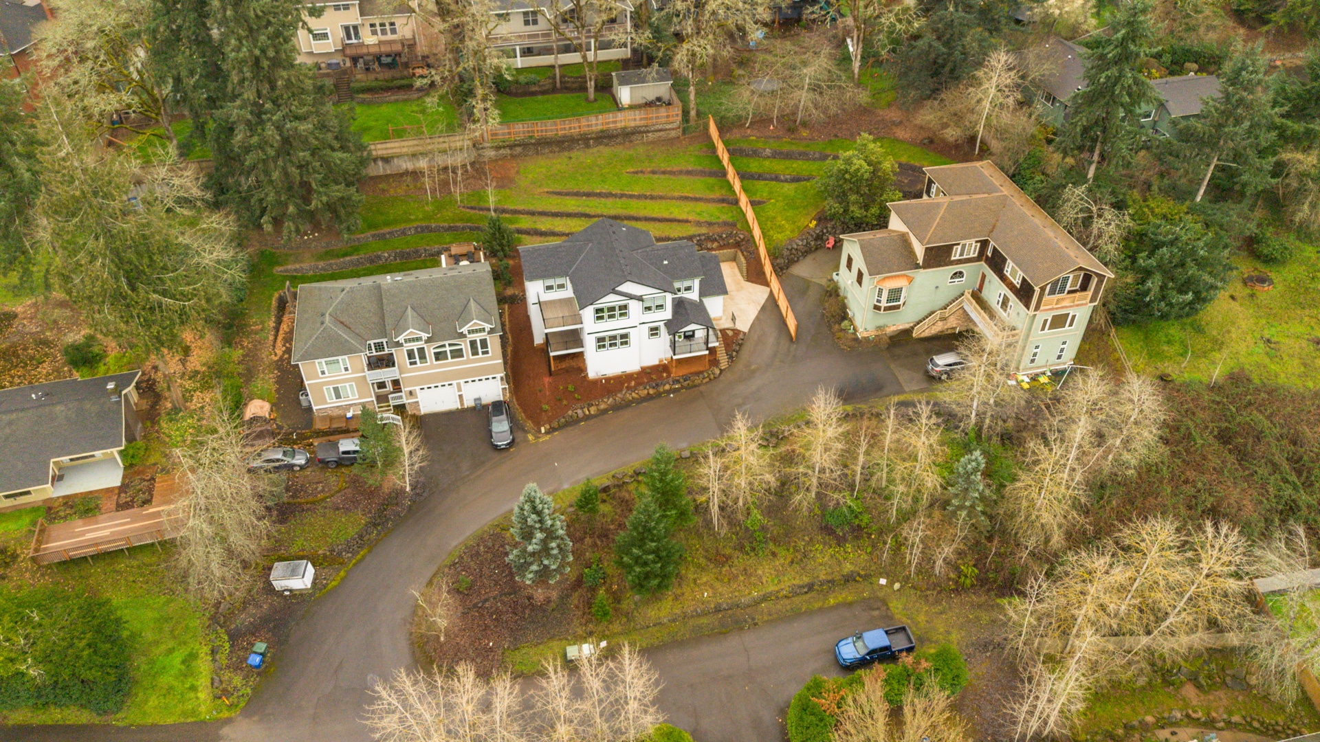Aerial view of a quiet residential property surrounded by lush landscaping and mature trees in a peaceful neighborhood setting.
