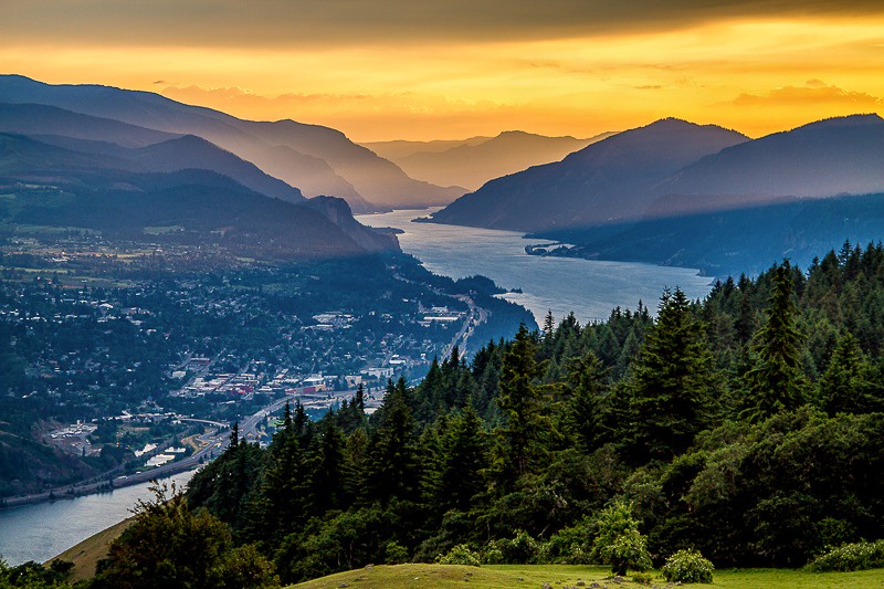 Sunset over the Columbia river framed by forested mountains
