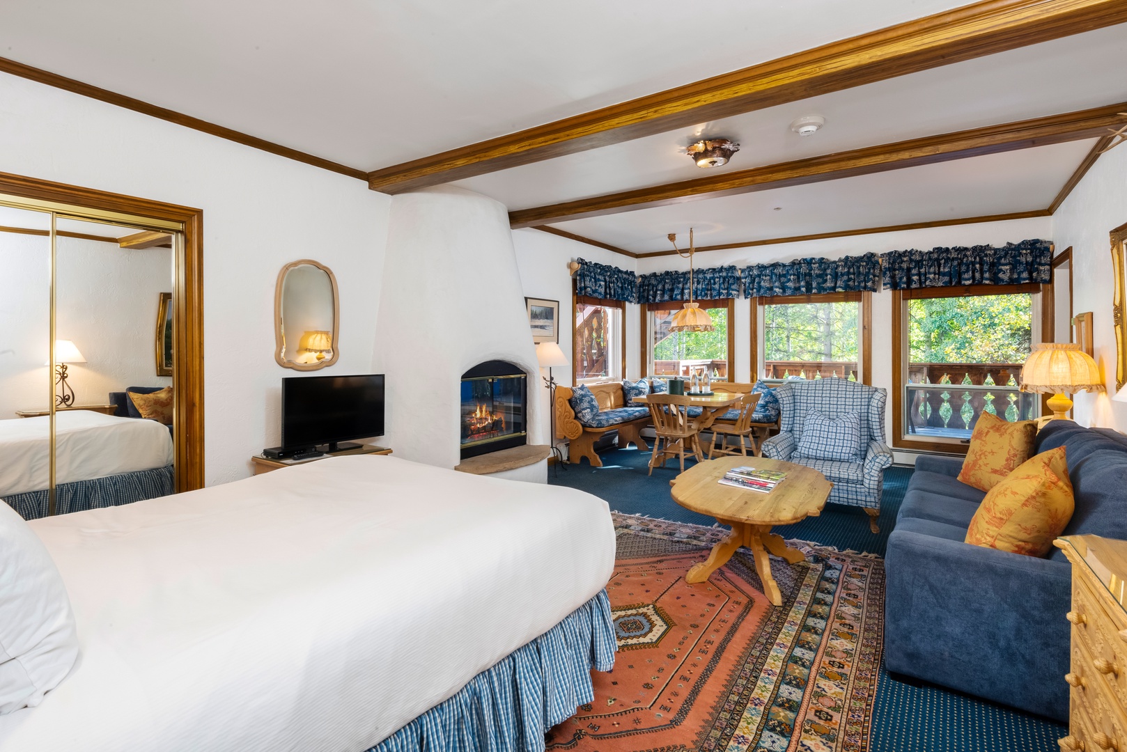 Sink into cozy alpine charm with a plush bed, crackling fireplace, and your own dining nook framed by forest views through warm wood windows.