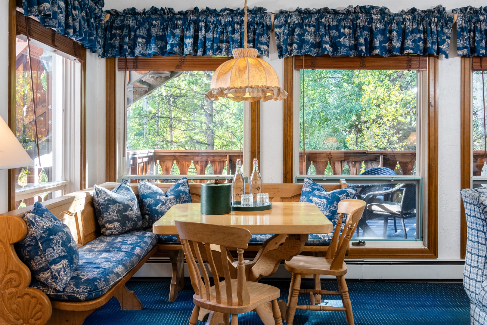 Gather at your cozy window-side dining nook with built-in seating and forest views. The space invites you to enjoy meals together while surrounded by charming alpine-inspired décor and natural light.