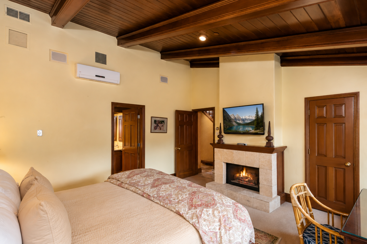 Unwind in your spacious bedroom featuring a cozy fireplace, flat-screen TV, and cathedral ceilings with exposed beams. Air conditioning keeps you comfortable year-round.