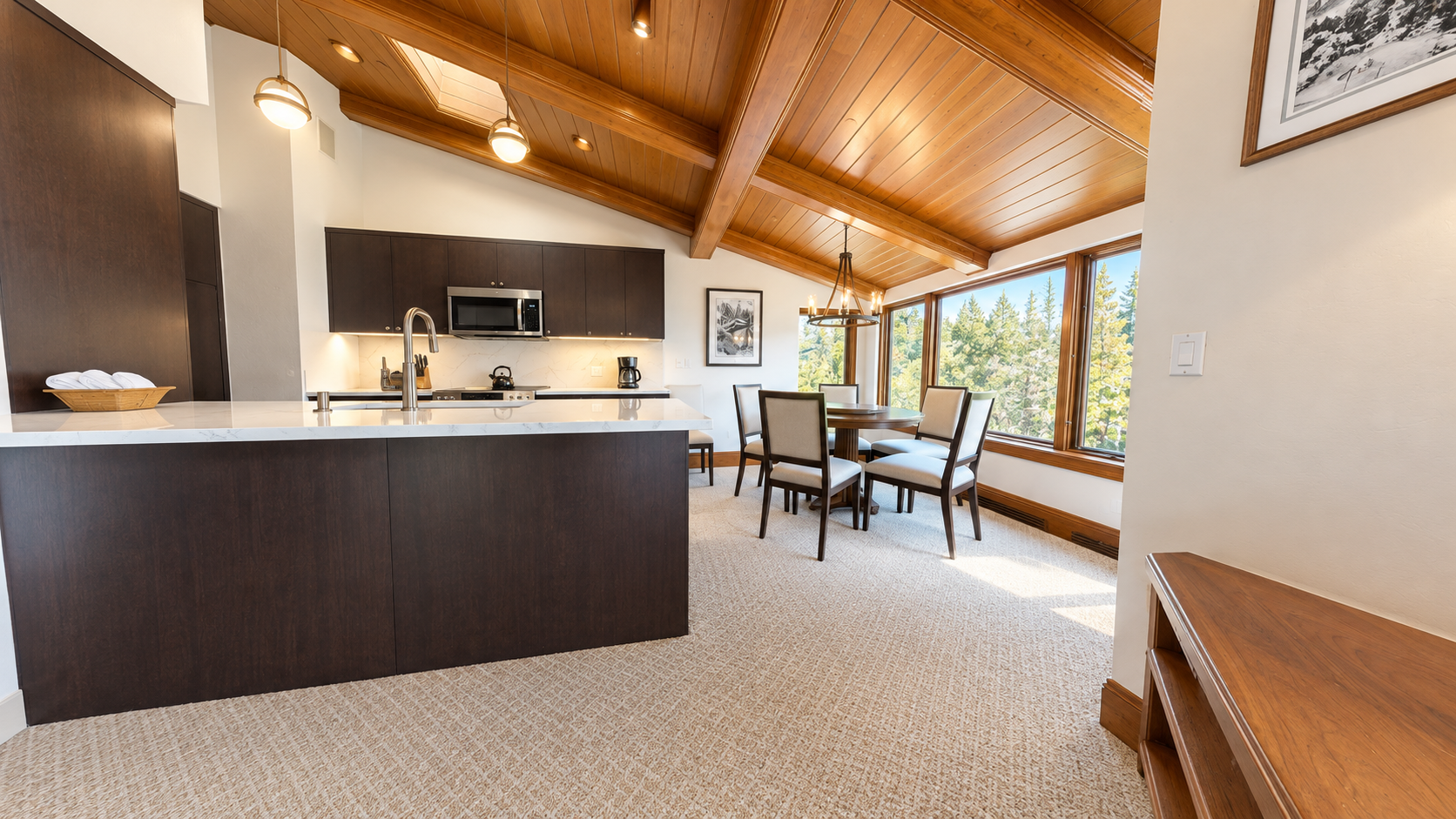 Gather under soaring wood ceilings in your open kitchen and dining area, where natural light pours through large windows framing treetop views—perfect for leisurely meals and memorable moments together.