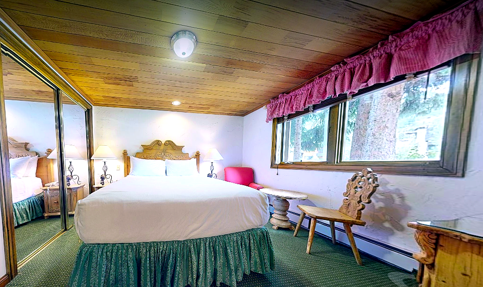 Cozy alpine charm welcomes you with crisp linens, warm wood paneling, and a garden view window that frames natural light—your peaceful retreat awaits.