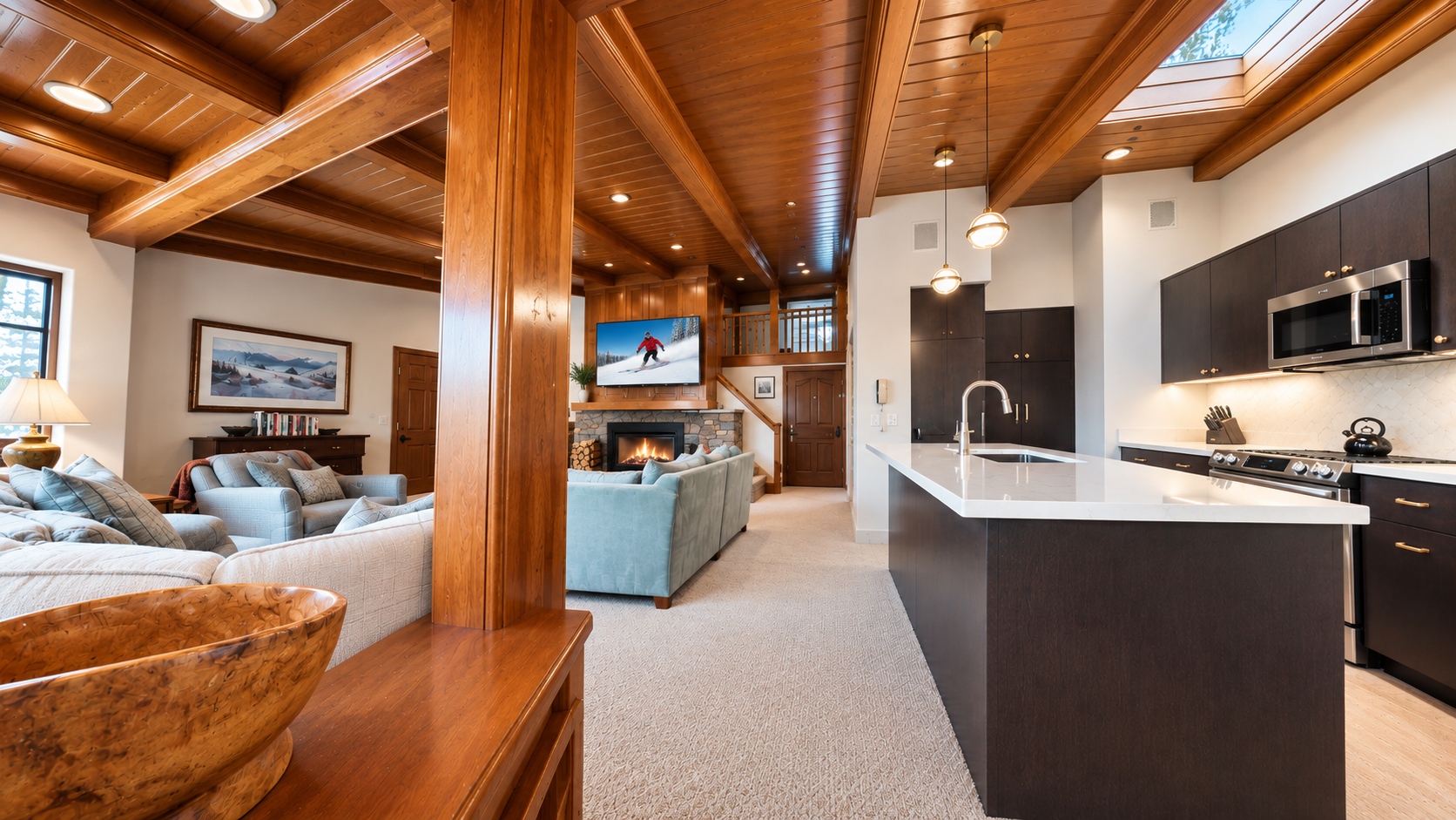 Soaring wood-beamed ceilings frame your open-concept retreat, where the living area flows into a sleek modern kitchen. Cozy up by the fireplace or prepare meals at the spacious island—all under the warm glow of mountain-style elegance.