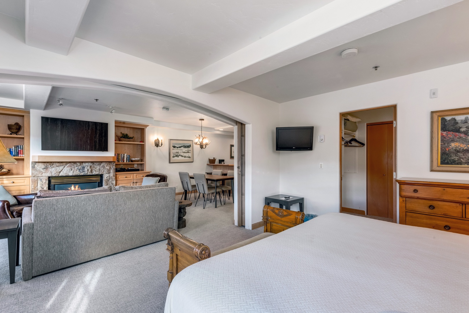 Your spacious suite flows seamlessly from bedroom to living room, where a stone fireplace adds warmth, elegant furnishings invite relaxation, and thoughtful details promise comfort at every turn.
