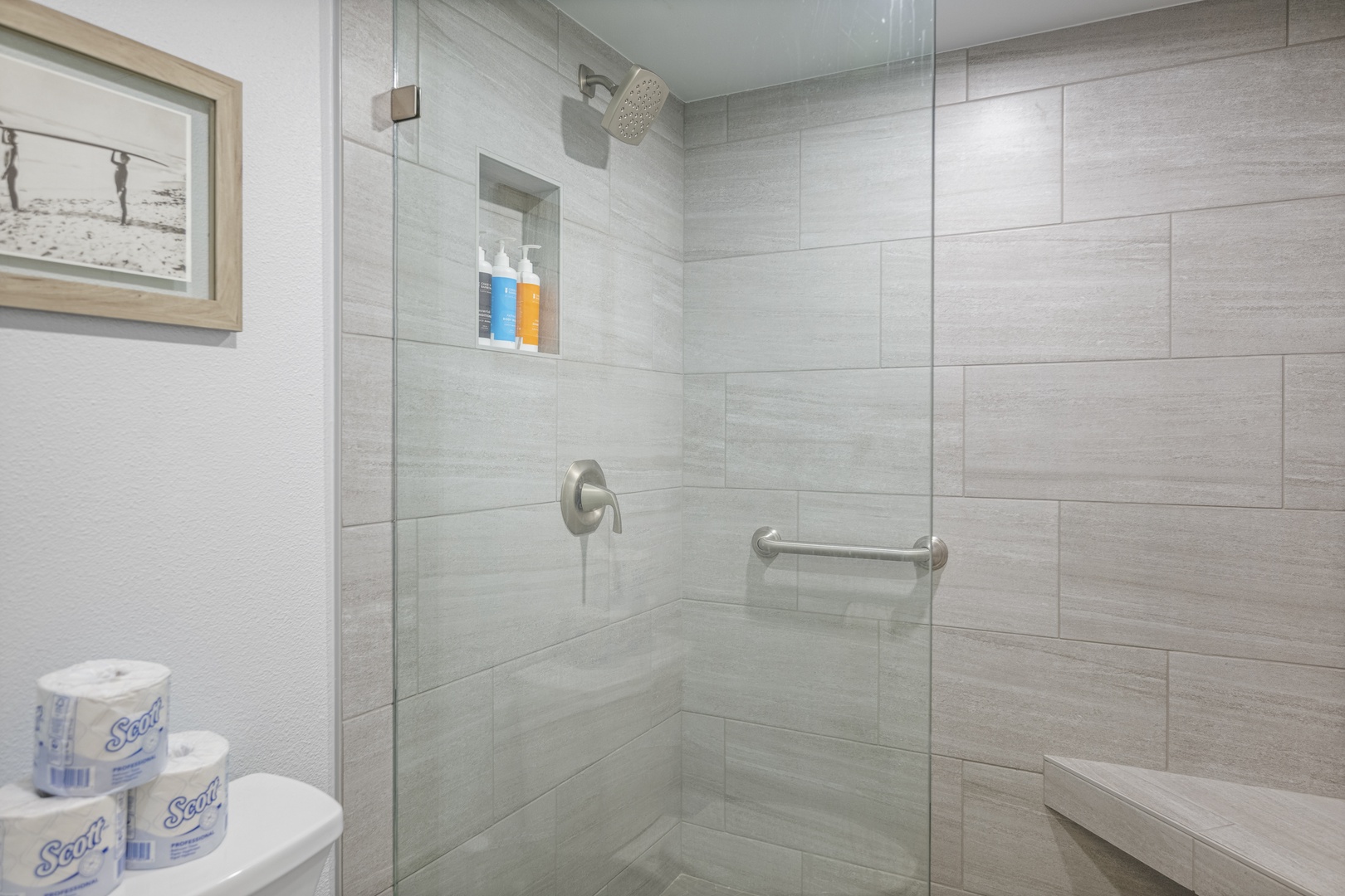 Your bathroom features a sleek walk-in shower with a convenient built-in seat and grab bar, finished in elegant neutral tiling. Plush Scott towels await your arrival.
