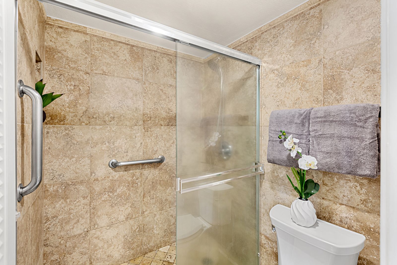 Step into your spa-like bathroom retreat with elegant stone walls and a spacious glass shower for ultimate relaxation.
