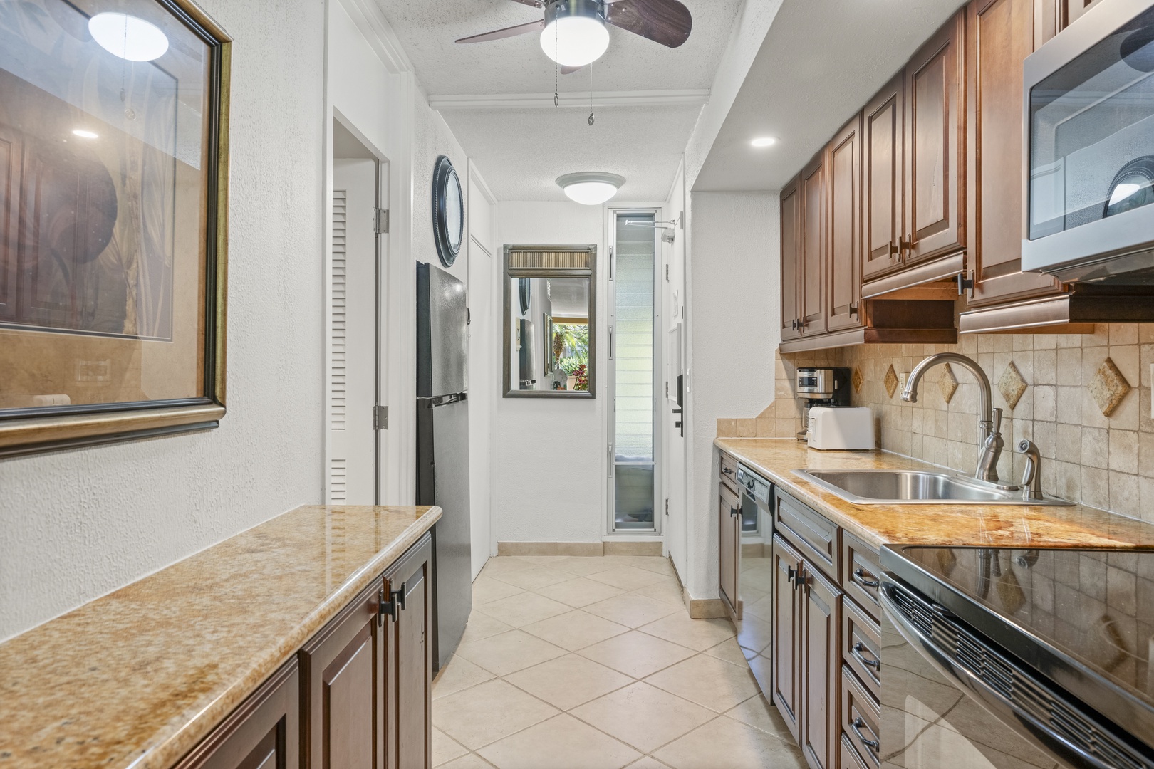 Your fully equipped galley kitchen features warm wood cabinetry, granite countertops, and modern appliances—ready for preparing quick breakfasts or leisurely meals during your stay.