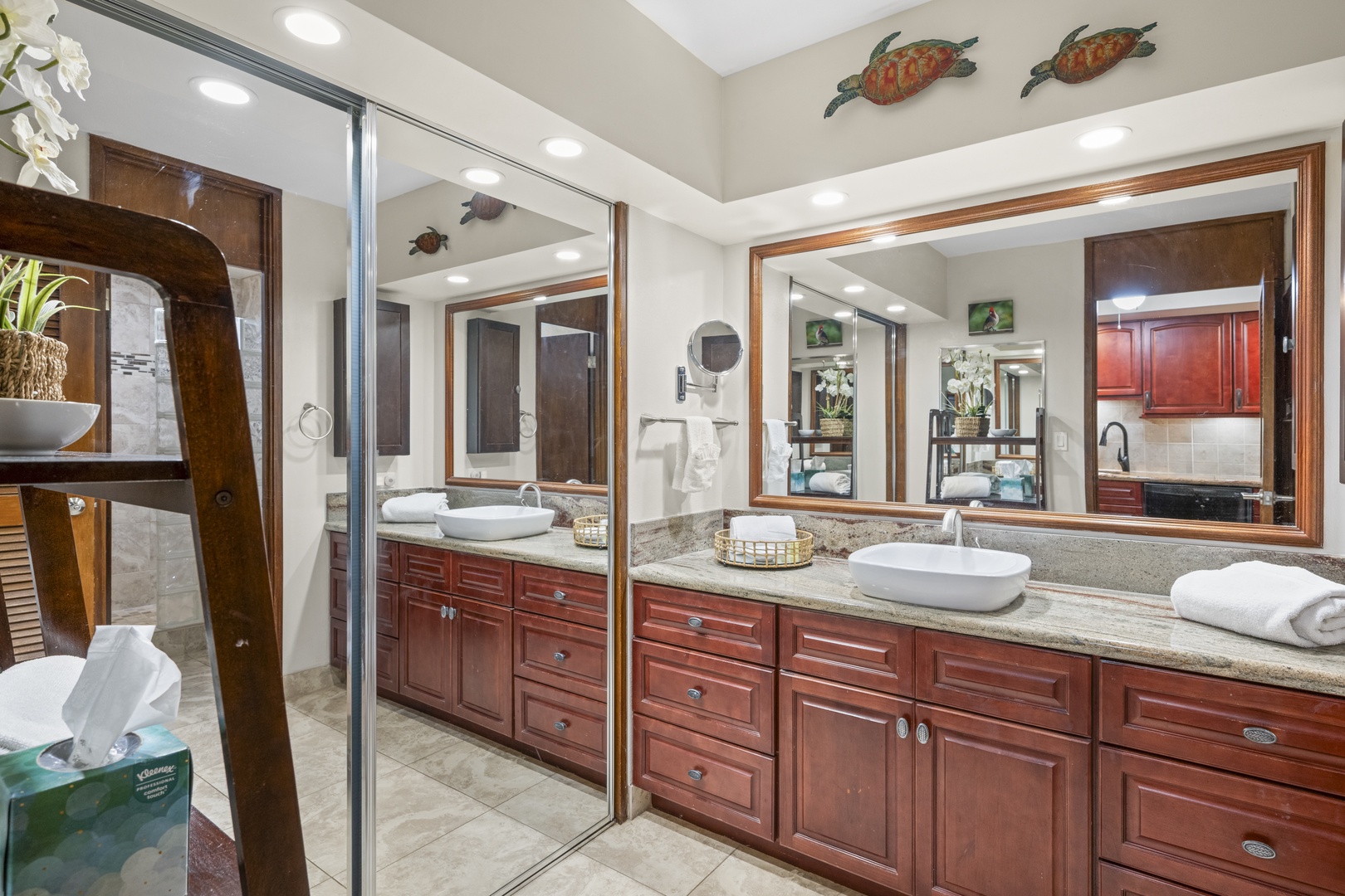 Unwind in your spacious bathroom featuring dual vessel sinks, granite countertops, rich wood cabinetry, and coastal-inspired sea turtle art. Fresh towels and thoughtful amenities await your arrival.