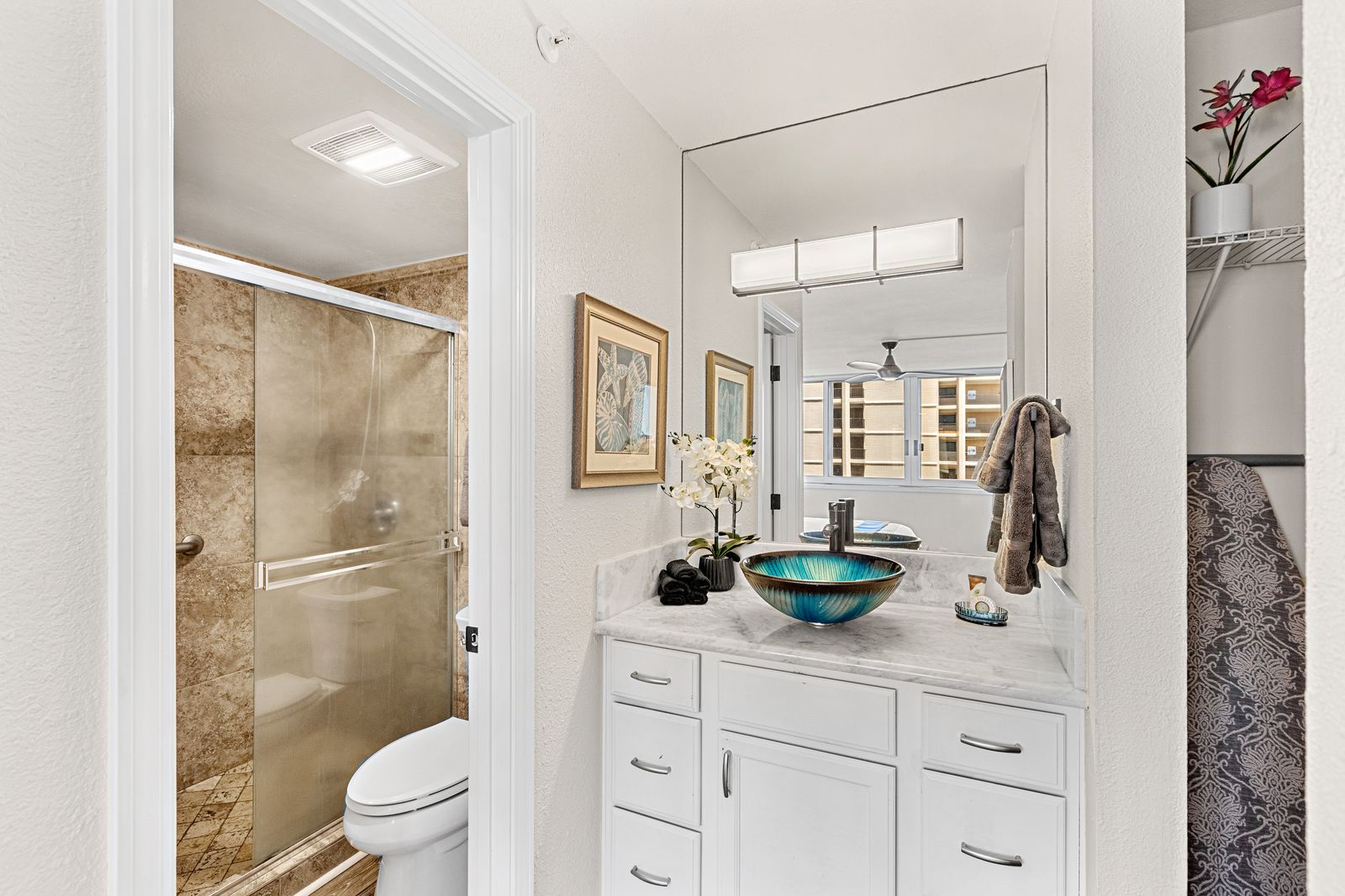 Luxuriate in your elegant bathroom featuring a stunning glass vessel sink, marble countertops, and spa-like ambiance.