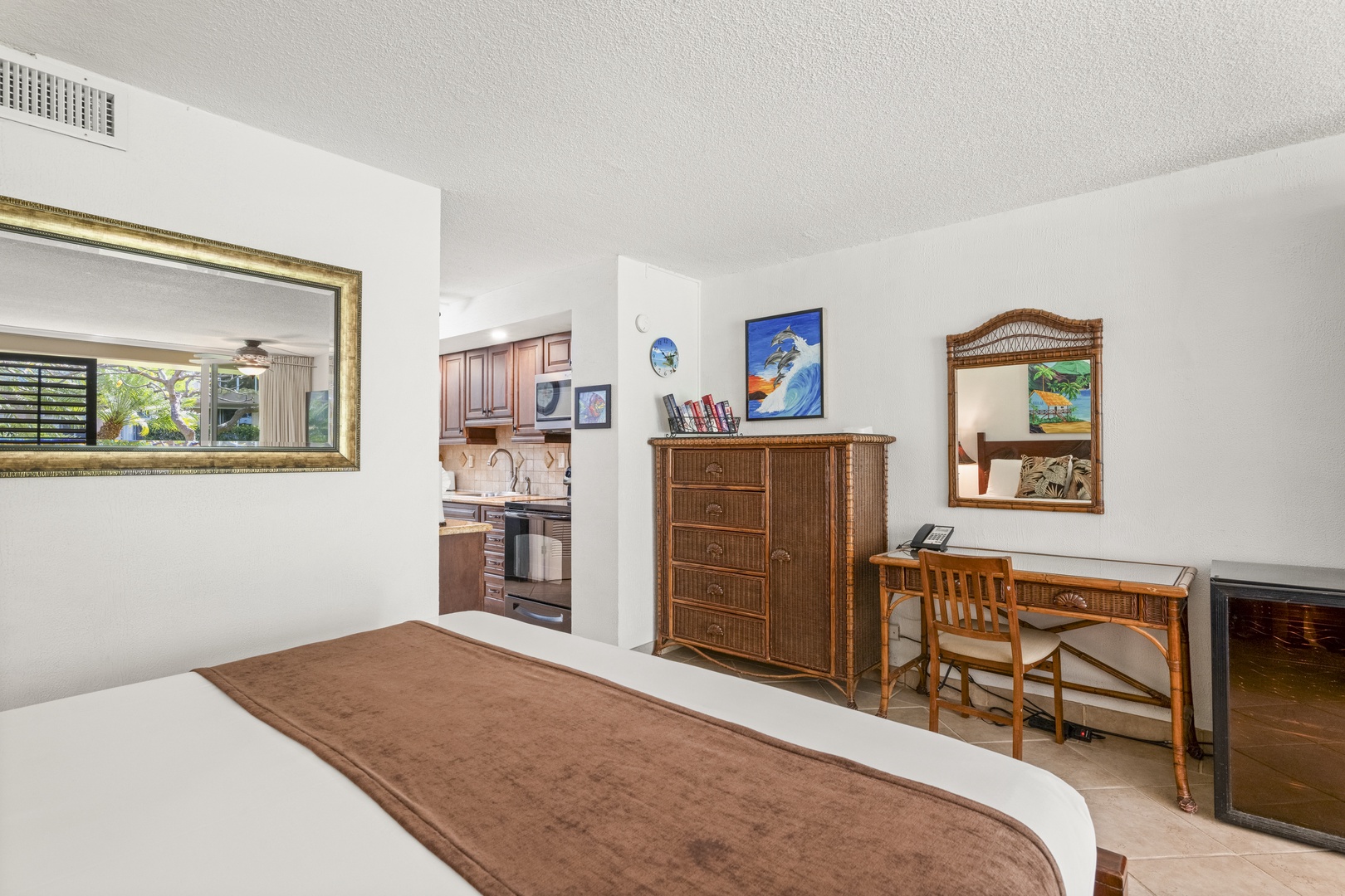 Relax in your cozy bedroom with tropical-themed décor, a dedicated workspace, and a view into the fully-equipped kitchen—perfect for unwinding after a day of adventure.