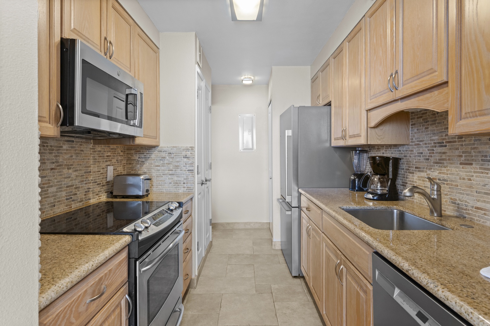 Your fully equipped galley kitchen features granite counters, stainless appliances, and elegant stone backsplash—perfect for preparing memorable meals.