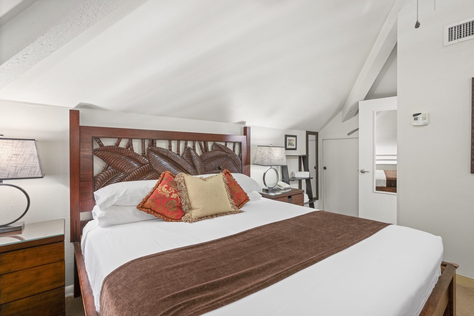 Step into your cozy loft retreat with vaulted ceilings and a beautifully crafted bed that invites restful nights. The warm wood headboard and soft linens create the perfect sanctuary for relaxation.