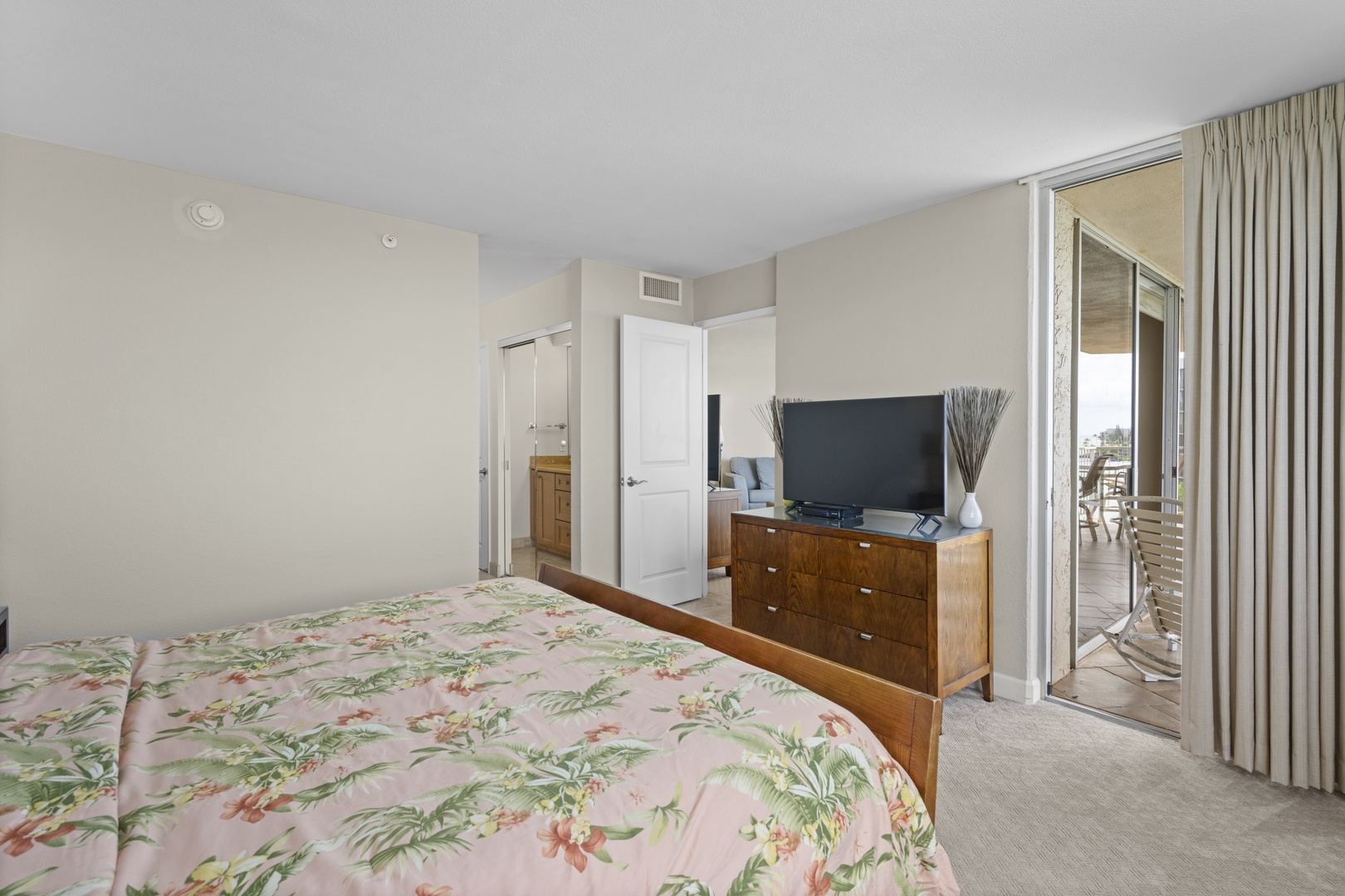 Your peaceful bedroom features tropical-print bedding, polished wood furnishings, and direct balcony access where ocean breezes await.