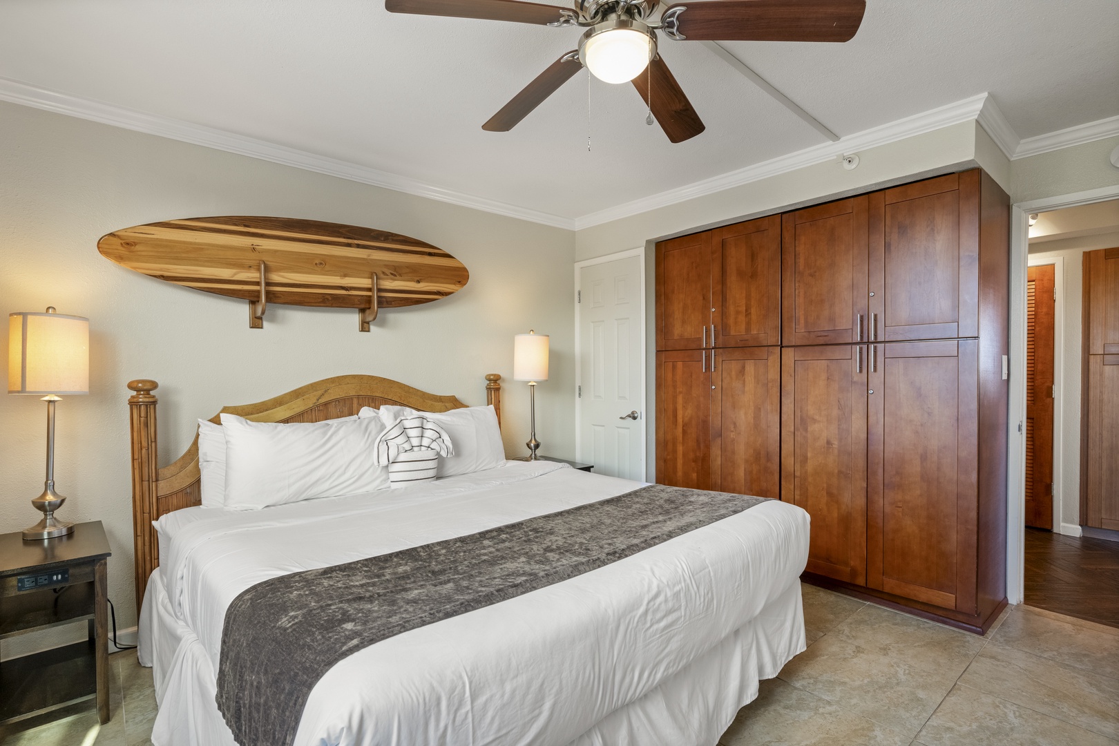Sink into crisp white linens and let the ceiling fan lull you to sleep in this coastal-inspired bedroom, complete with surfboard décor and generous wardrobe space for all your vacation essentials.