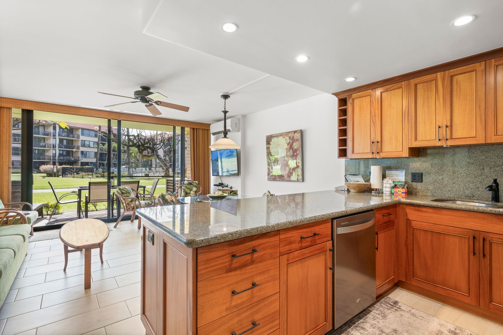 Picture yourself preparing meals in this inviting kitchen with granite counters and warm wood cabinetry, opening to a bright dining area with garden views beyond.