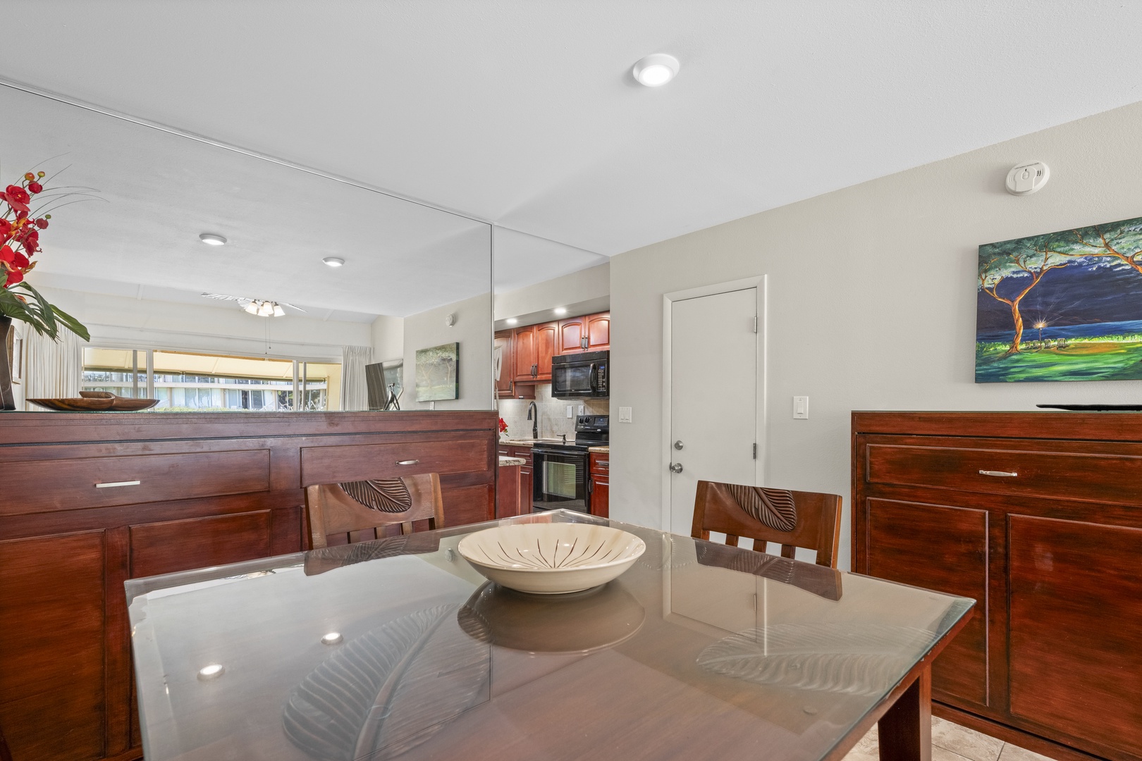Picture yourself enjoying meals at this elegant glass dining table, surrounded by warm wood tones and fresh orchids, with the fully-equipped kitchen just steps away.