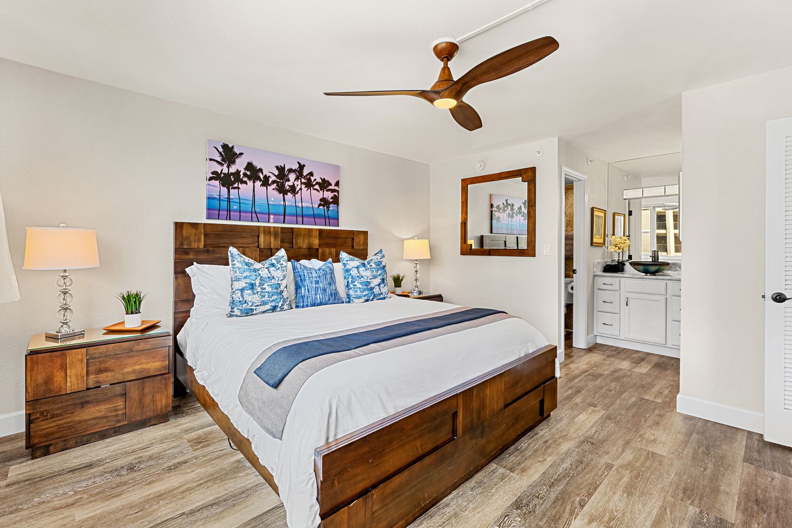 Relax in your bright bedroom featuring a comfortable king bed, tropical artwork, and a ceiling fan to keep you cool.
