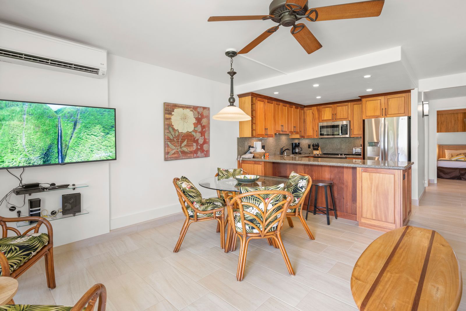 Step into your open-plan living space where warm wood tones and tropical breezes meet. Cook in your full kitchen, dine with views of lush greenery, and relax in air-conditioned comfort under charming ceiling fans.
