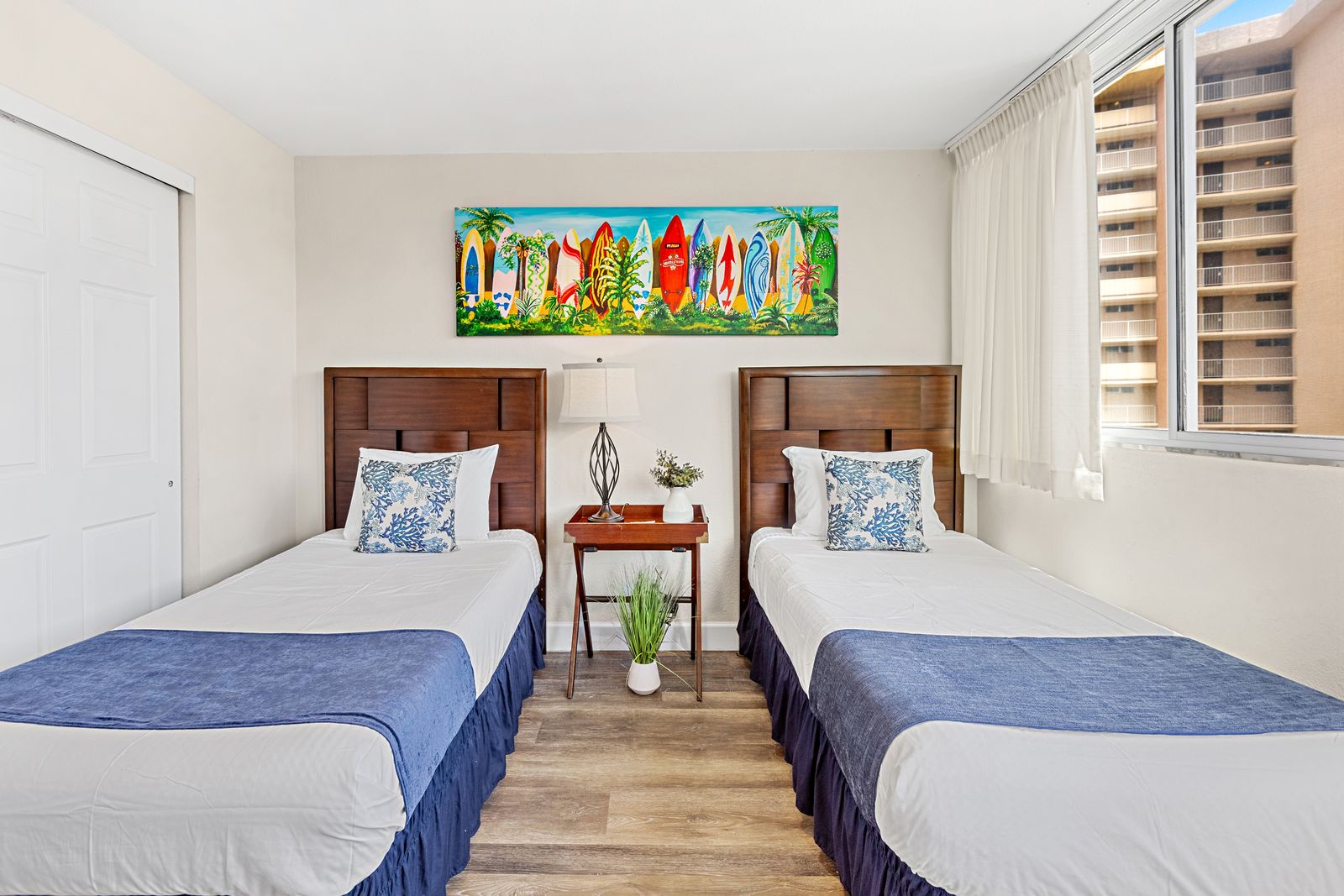 Wake up in your bright, coastal-themed bedroom with twin beds, tropical artwork, and city views from your window.