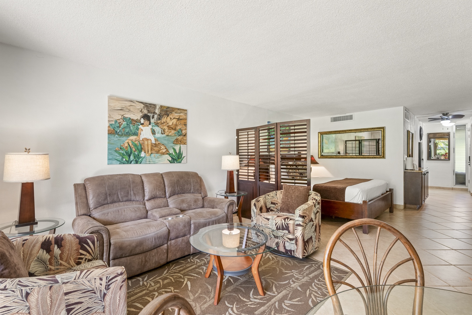 Settle into your tropical retreat—open floor plan connects cozy living space with bedroom, accented by island artwork and warm wood tones.