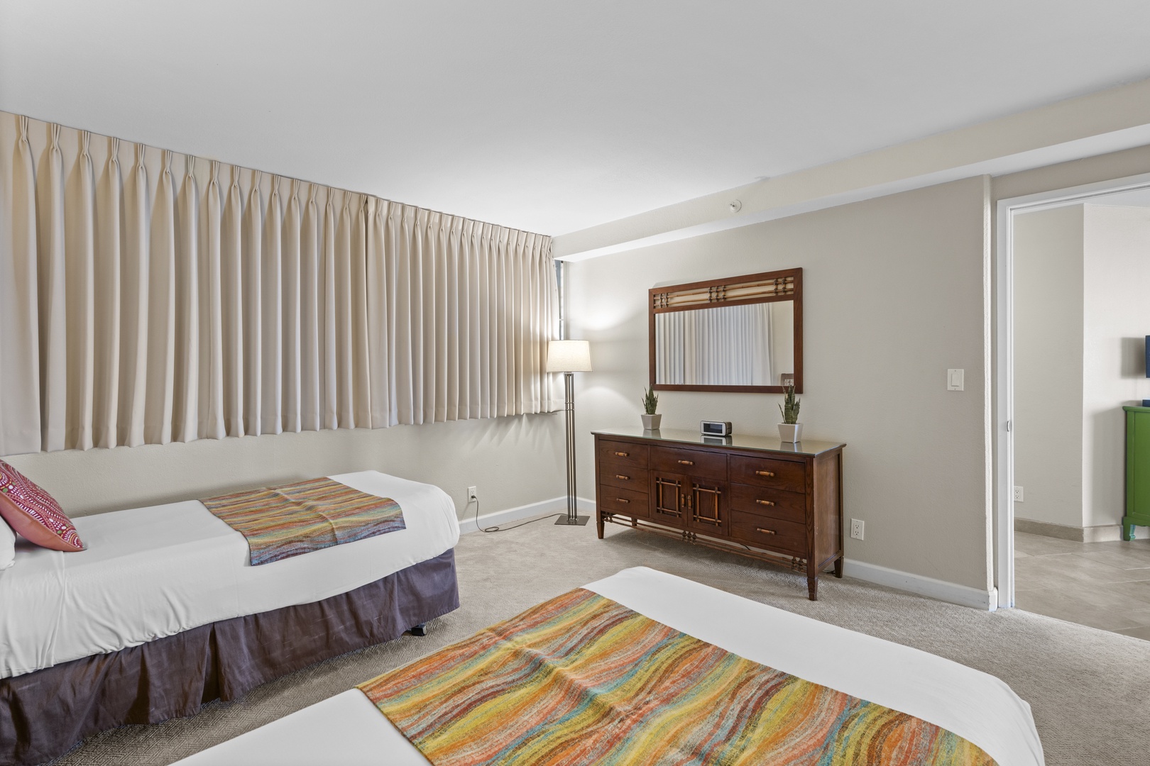 Your spacious retreat features twin beds with colorful accents, elegant wood furnishings, and soft lighting for peaceful nights.