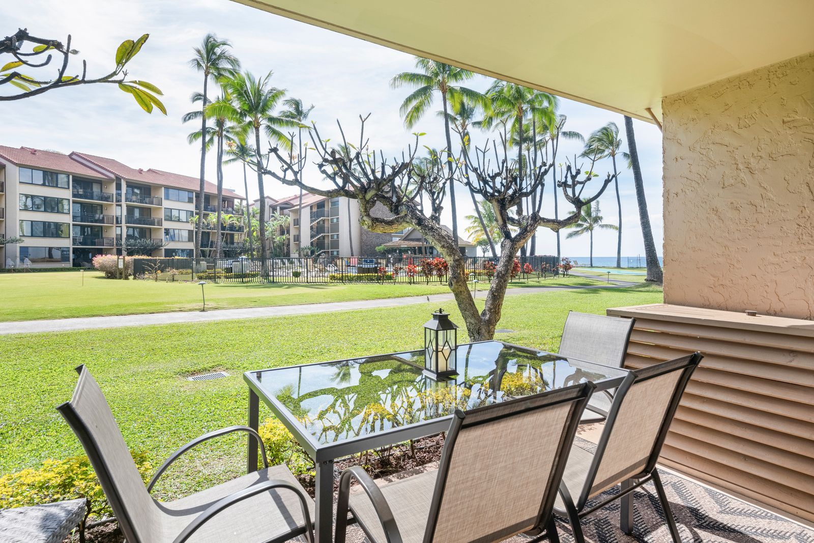 A charming covered balcony provides the ideal spot to relax with morning coffee or evening drinks while overlooking lush tropical grounds and the sparkling ocean beyond.