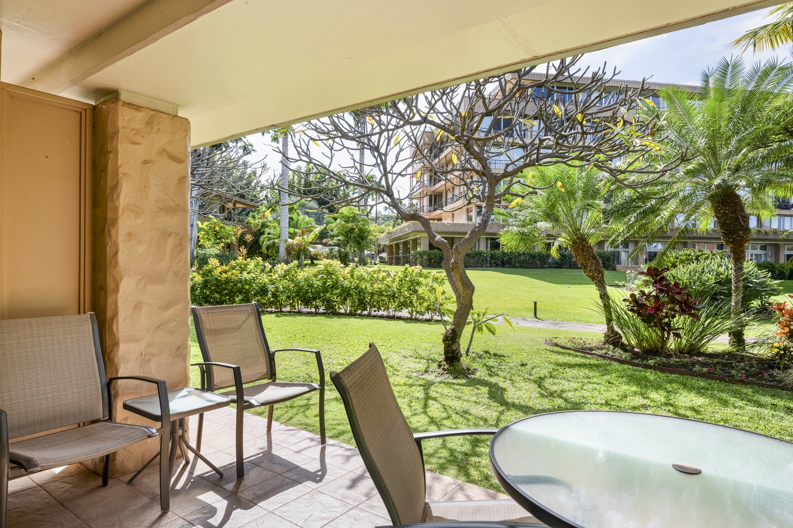 Your private patio overlooks lush gardens with tropical palms and sculptural trees, offering a peaceful spot to unwind with morning coffee or evening conversation.