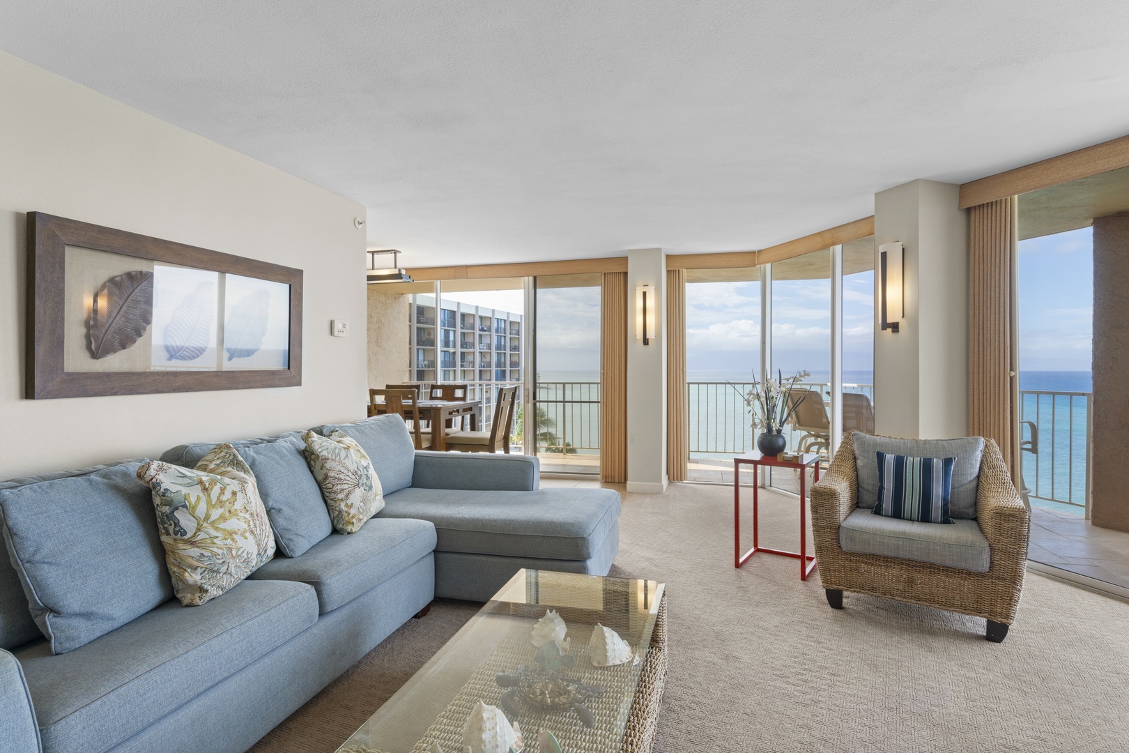 Unwind in your elegant oceanfront living room where floor-to-ceiling windows frame endless sea views and comfortable seating invites relaxation.