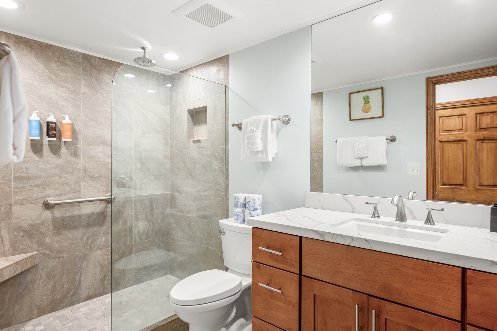 Unwind in your private spa-like bathroom, featuring a spacious walk-in shower, elegant marble countertops, and warm wood accents that create a serene, luxurious retreat.