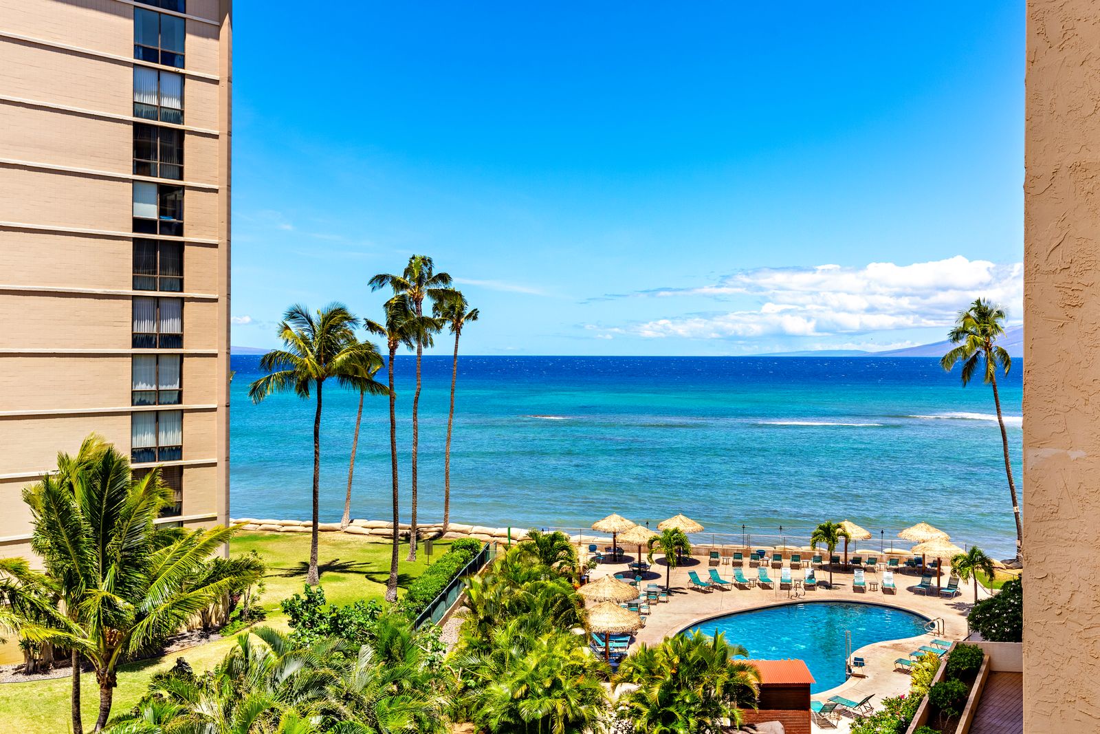 Stunning oceanfront resort view featuring turquoise waters, swaying palms, and pristine beachfront with pool deck and tropical landscaping.
