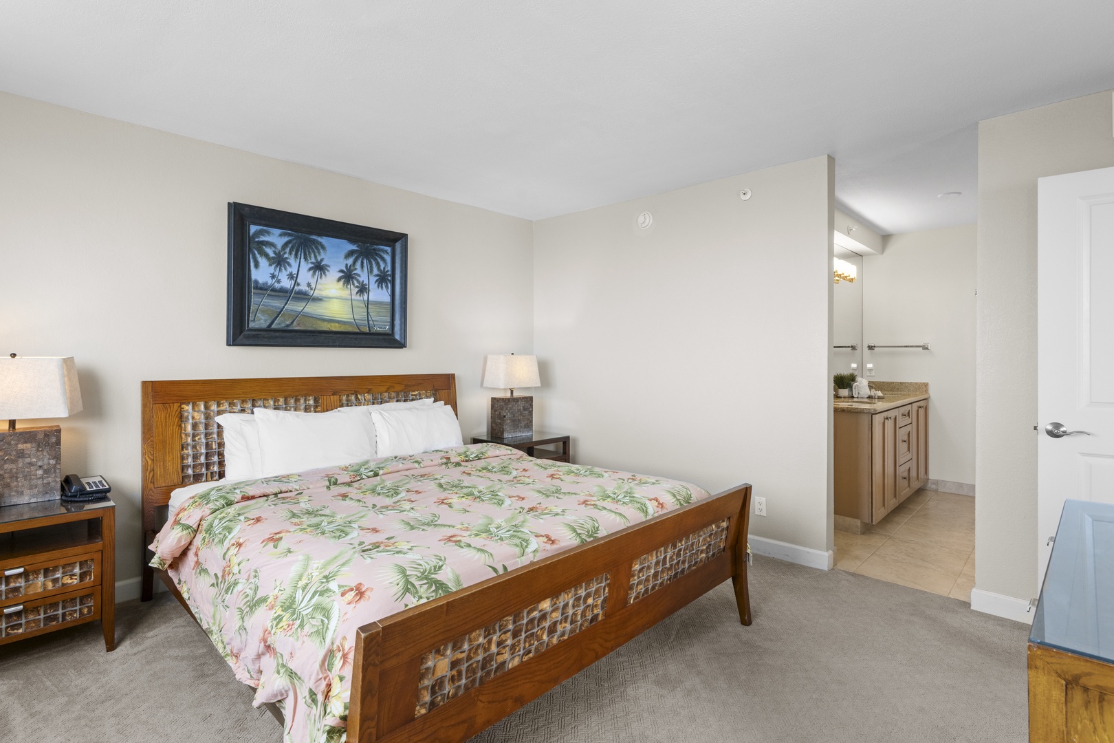 Relax in your peaceful bedroom featuring tropical artwork and comfortable furnishings, with a convenient kitchenette just steps away.