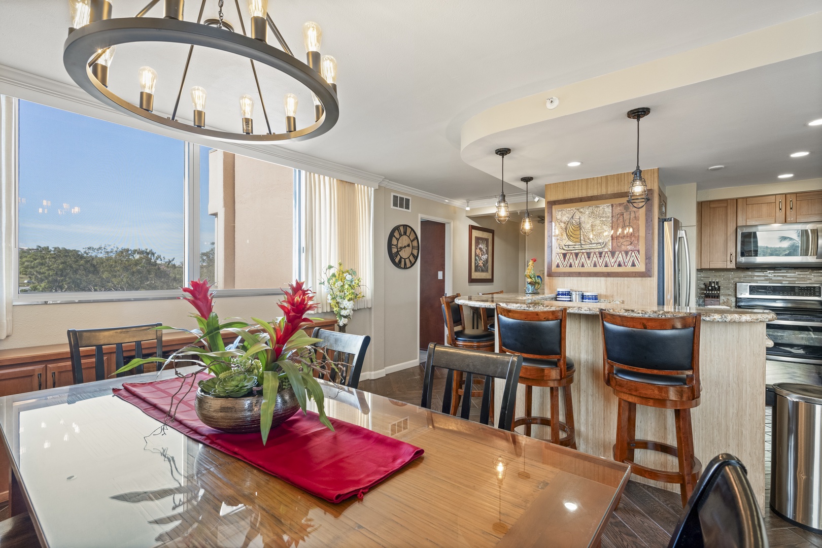Sunlit open living with a dining table, breakfast bar, and natural treetop views—your perfect spot for morning coffee and evening meals.